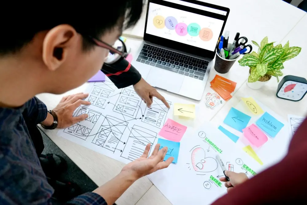 Man designing wireframes at desk with laptop, illustrating UI/UX design bootcamps
